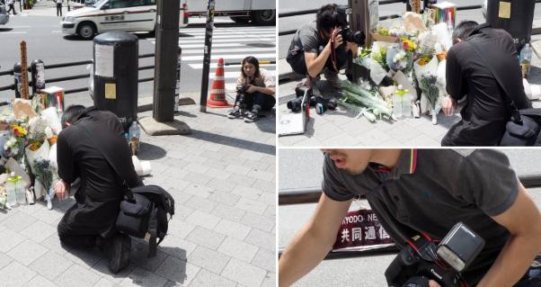 共同通信のカメラマンが献花台の脇にしゃがみこみ祈る関係者の顔を前から撮影。